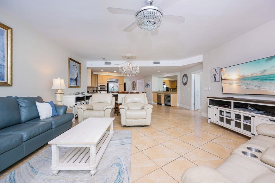 Living room features plush seating, a large TV, and a stylish chandelier, perfect for relaxation and entertainment