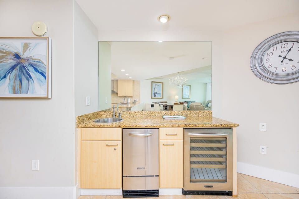 Stylish wet bar features granite countertops, stainless appliances, and a lovely view into the living area