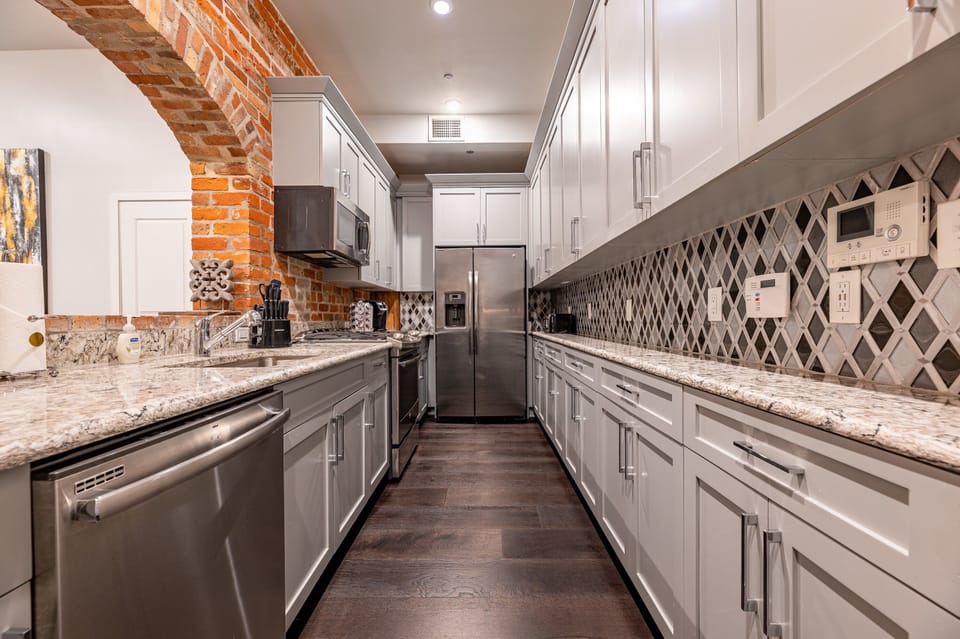 Galley-style, fully equipped kitchen with an open flow to the living/dining area. Stocked with essentials from mixing bowls to wine glasses, featuring stainless steel appliances, stone countertops, and a tile backsplash for a luxurious feel!