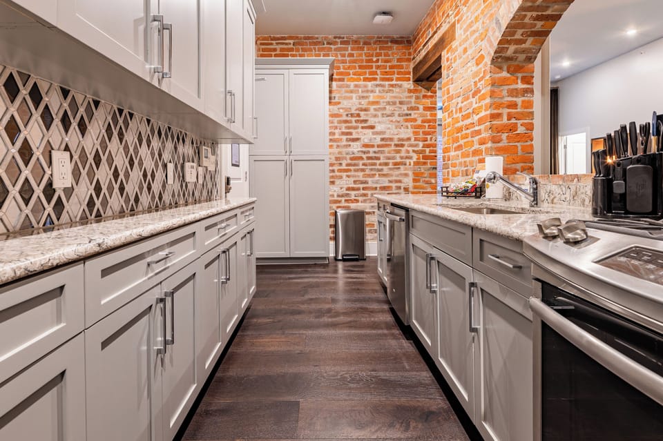 Galley-style, fully equipped kitchen with an open flow to the living/dining area. Stocked with essentials from mixing bowls to wine glasses, featuring stainless steel appliances, stone countertops, and a tile backsplash for a luxurious feel!