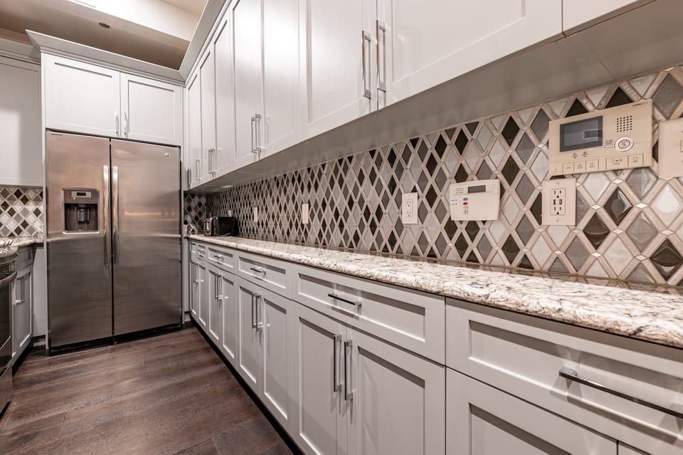 Galley-style, fully equipped kitchen with an open flow to the living/dining area. Stocked with essentials from mixing bowls to wine glasses, featuring stainless steel appliances, stone countertops, and a tile backsplash for a luxurious feel!