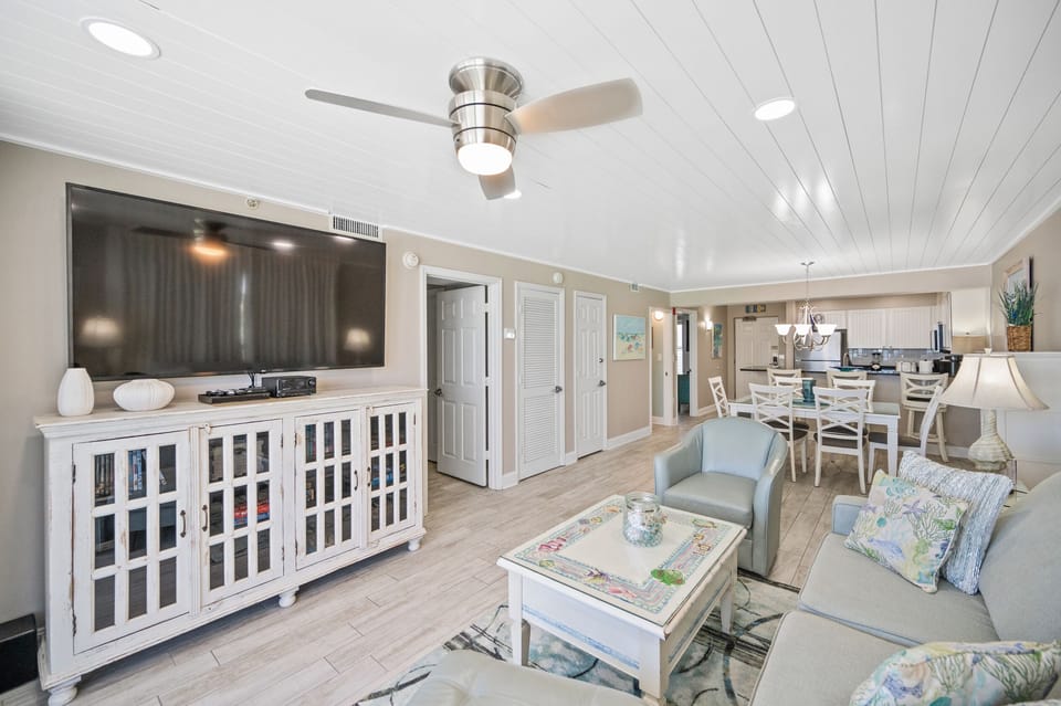 Living room with 85" TV, dining area, and kitchen