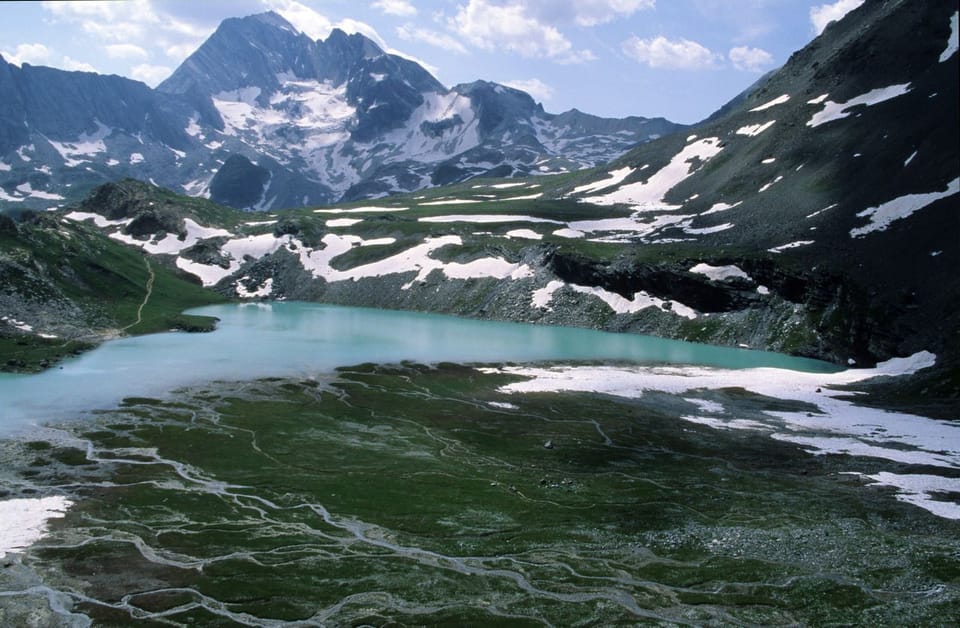 A glacial lake shimmers in the summer landscape of the Vanoise National Park, a stunning natural wilderness on the doorstep of Plagne Center.
