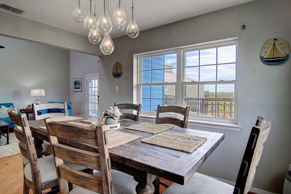 You'll love gathering around this rustic dining table under elegant pendant lights, with coastal views streaming through windows.