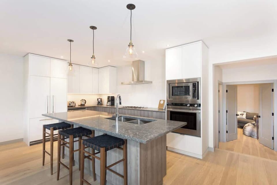 - Breakfast bar seating under warm pendant lights and wood floors  
- Spacious island perfect for casual dining or morning coffee  
- Connects seamlessly to the open living area for social moments 