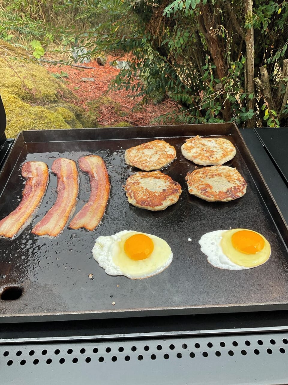 Flat-top griddle for bacon, eggs and breakfast patties outdoors.
