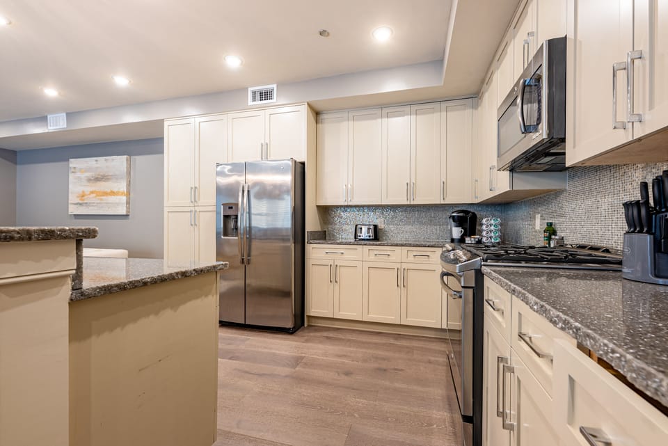 Cook and dine easily in the fully stocked kitchen, equipped with all stainless steel appliances, gas range, basic cookware, and a dining area for a comfortable meal at home. Entertain at the island with seating for three.