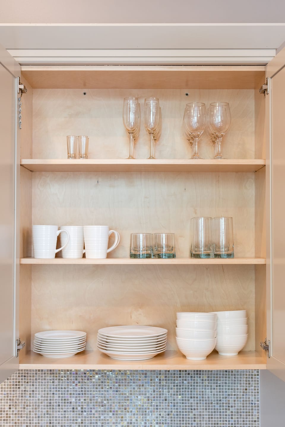 Galley-style kitchen with open flow to living/dining area. Fully stocked with essentials from mixing bowls to wine glasses. Features stainless steel appliances, stone countertops, and a stylish tile backsplash—perfect for cooking or hosting!