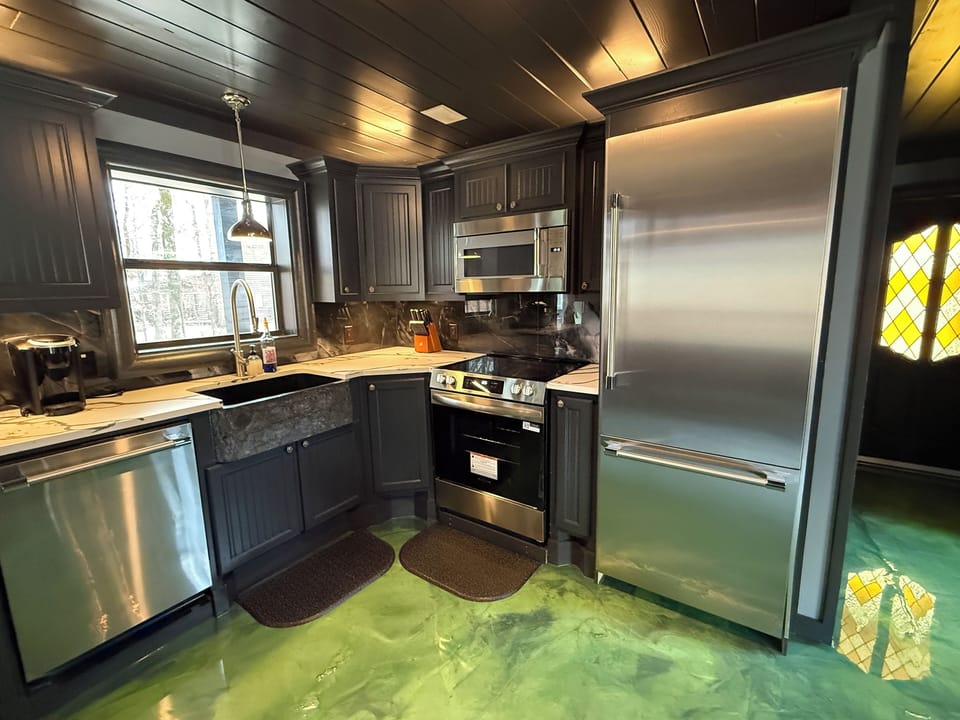 Cook your favorite meals in this sleek kitchen featuring quartz countertops, stainless steel appliances, and glowing epoxy floors.