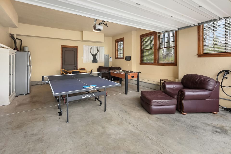 The 19th Hole: - Garage game room with ping-pong. foosball, seating, and an electric car charger.