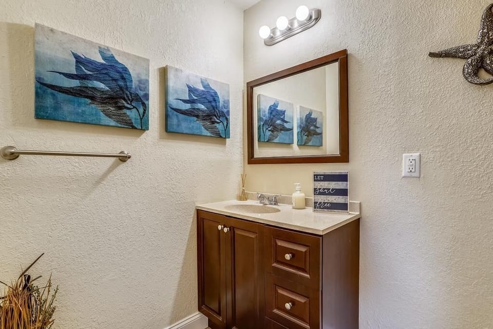 Unwind in your elegantly appointed bathroom, where coastal artwork and rich wood finishes create a serene, spa-like retreat for your stay.