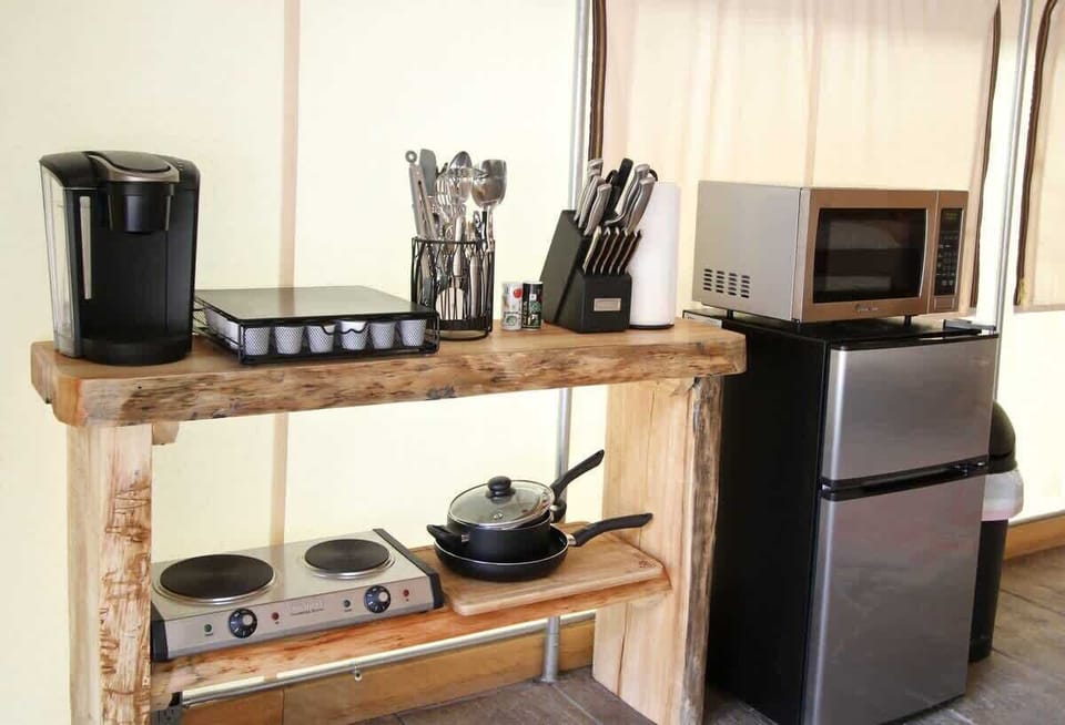 Well-stocked kitchen area with kitchenware, hot plate, utensils, cookware, and essentials for preparing simple meals during your glamping stay.