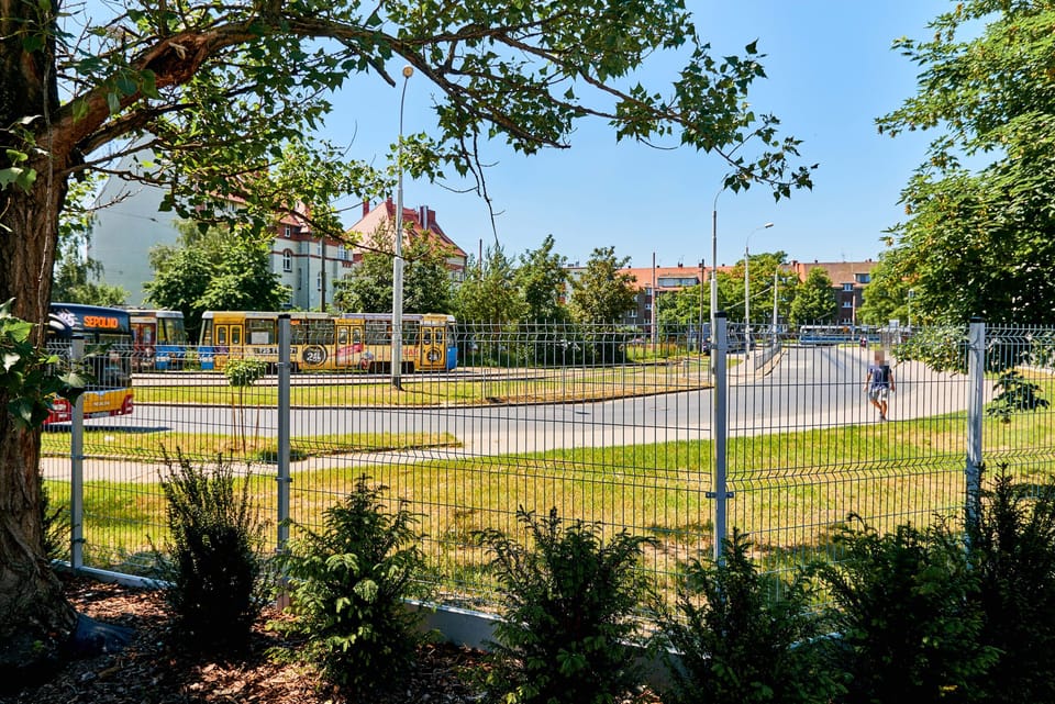 A view of the surrounding neighborhood, showing a park area with trees and open spaces. The area appears calm and residential.