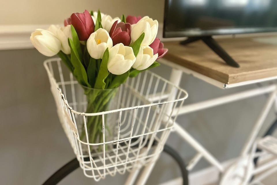 The Vintage Pedal bike's basket is adorned with tulips, repurposed as a TV stand