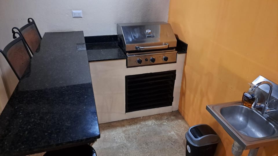 Granite bar with with seating and gas BBQ grill next to pool