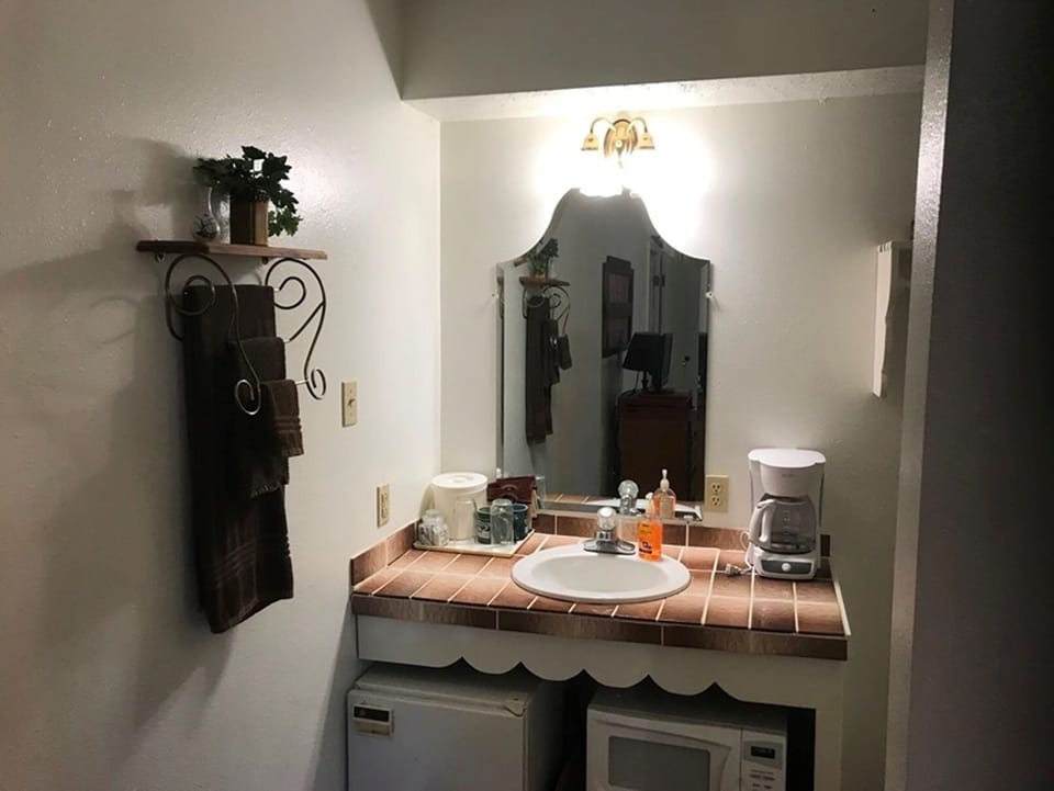 Custom tiled vanity with small fridge, microwave, and coffee maker.