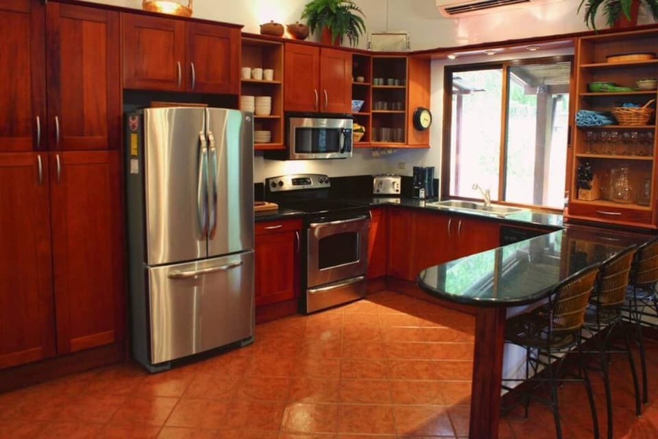 Fully equipped kitchen with modern appliances and ample workspace, perfect for preparing family meals or enjoying a private chef experience in your Costa Rican-style vacation home.
