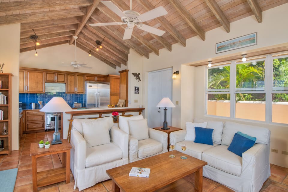 The living room offers comfy seating with Hunter fans, AC, screen doors & TV