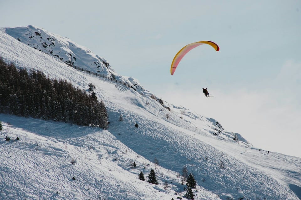 A paraglider soars above the snow-covered slopes of Les Deux Alpes, one of the French Alps' most popular year-round adventure destinations.