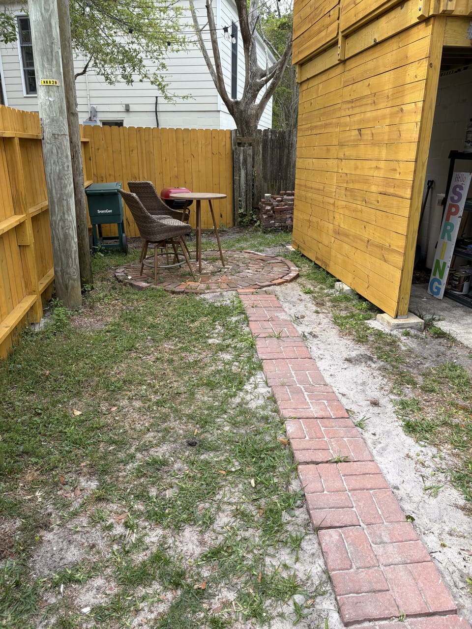 Private fenced yard with seating and charcoal grill.