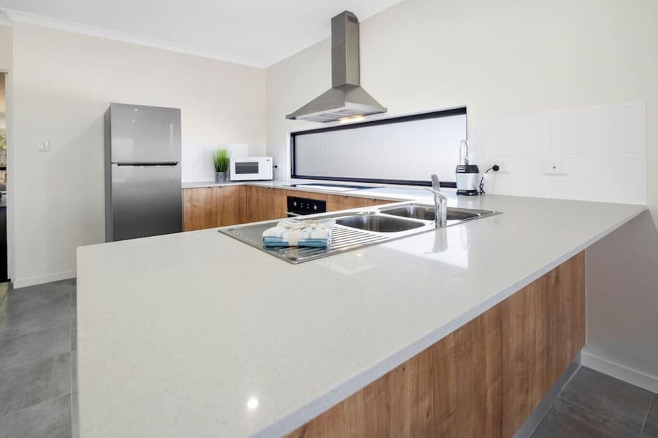 Large open plan kitchen  with modern oven cook top, microwave, blender, dishwasher, utensils and a fridge/freezer.