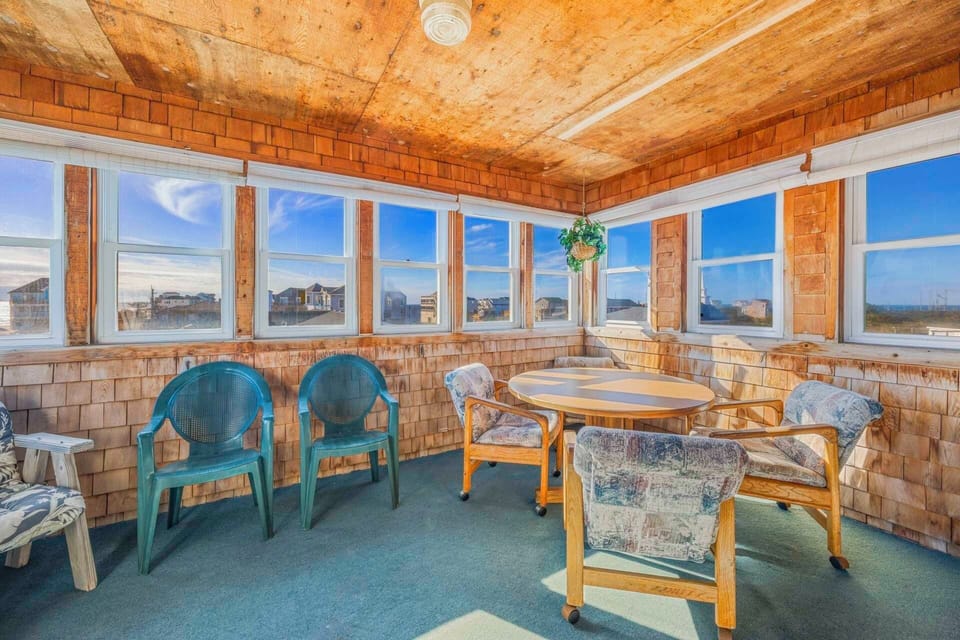 Settle into this cozy sunroom where large windows frame coastal views and comfortable seating invites you to relax with morning coffee or evening conversations.