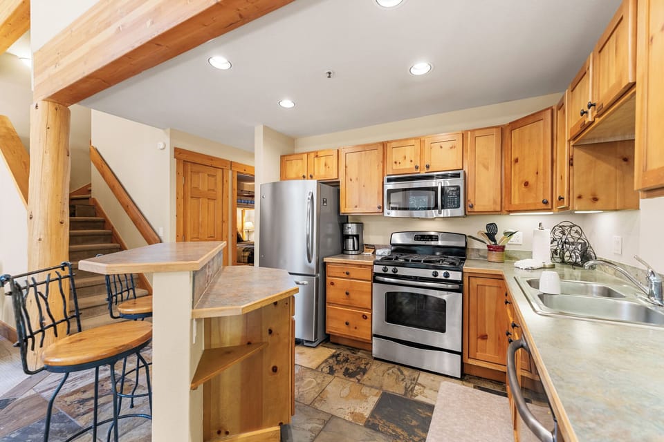 Cook memorable meals in your fully-equipped kitchen featuring warm wood cabinets, stainless steel appliances, and rustic exposed beams overhead.