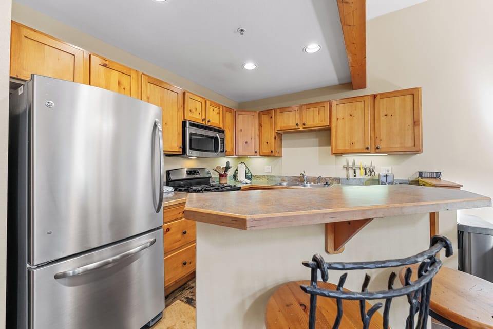 Your fully equipped kitchen features warm knotty pine cabinets, stainless steel appliances, and a breakfast bar perfect for morning coffee.