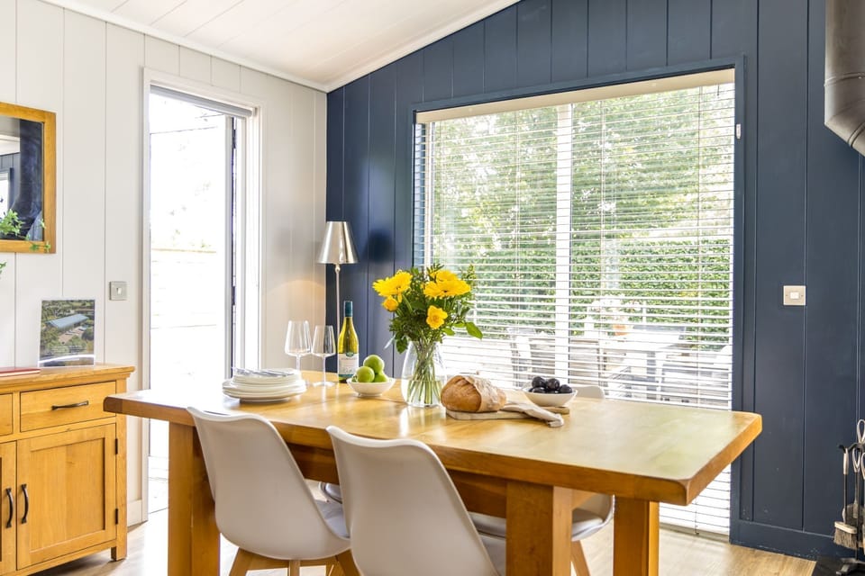 Dining table in bright open plan living with view of outdoor decking  - The Retreat