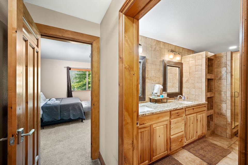Step into your spacious bathroom with granite counters, warm wood cabinetry, and a peaceful view into your cozy bedroom retreat.