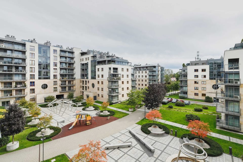 A closer view of the courtyard, featuring green spaces, benches, and colorful autumn trees.