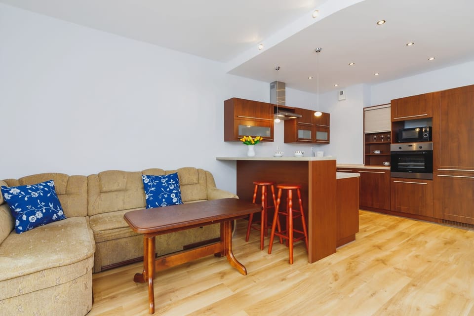 A functional living room with a kitchenette, wooden cabinets, and a dining area.