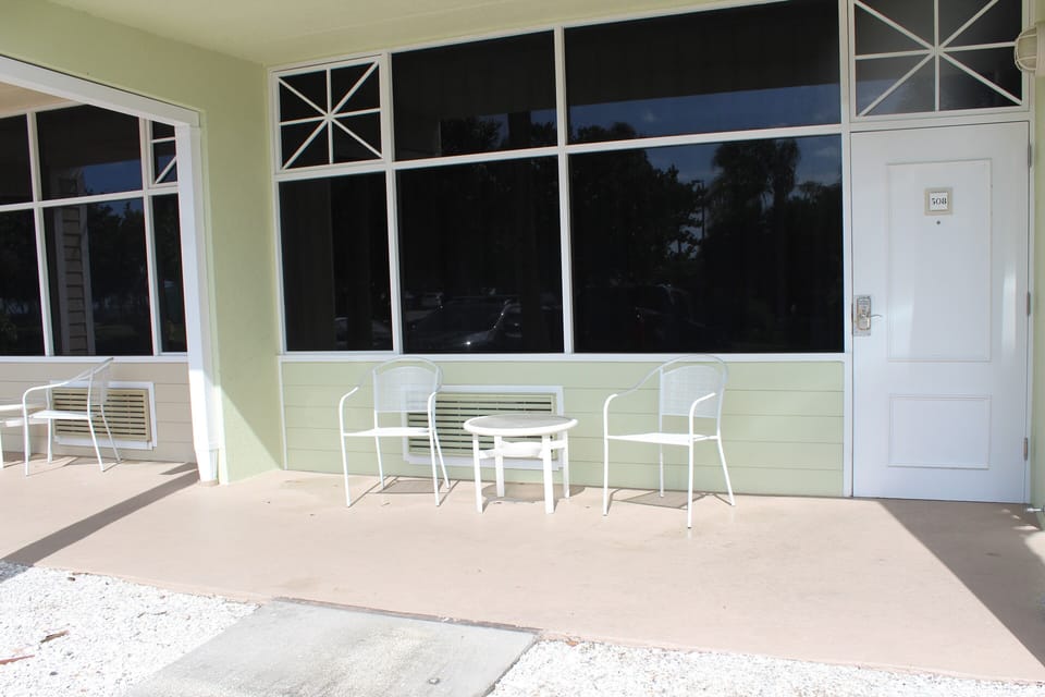 outside 2 chairs table looking out at resort water Pier parking in front condo 