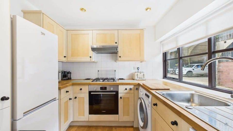 A modern, fully equipped farmhouse kitchen with an oven, dishwasher, washing machine, and microwave.