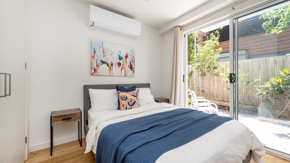 Bedroom 1 with split system and large class doors onto sunny courtyard