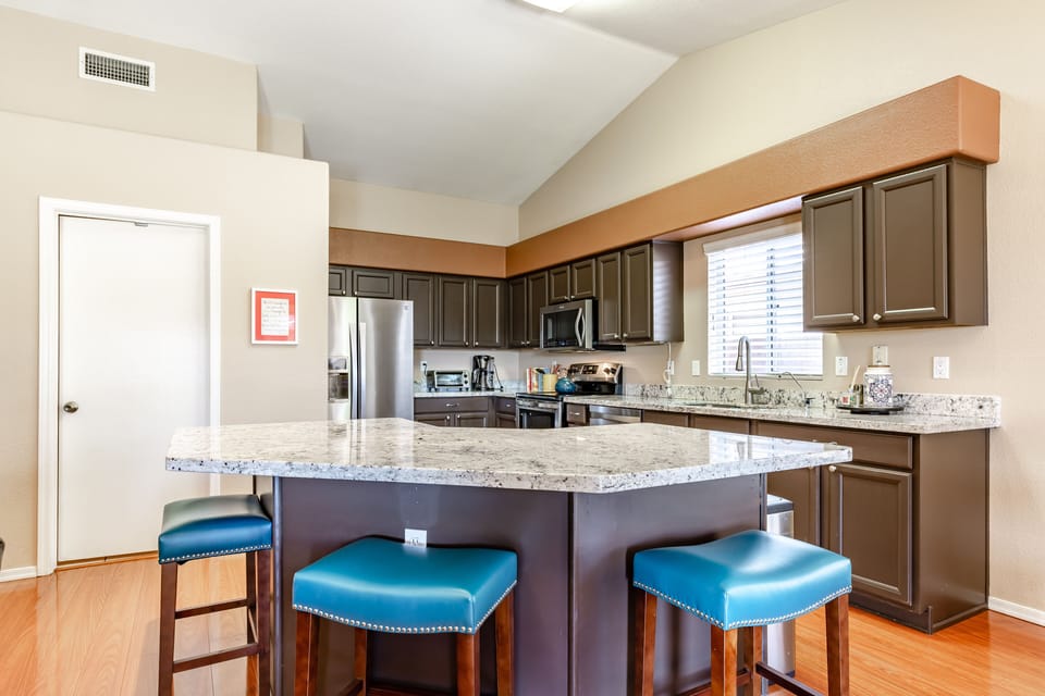 Spacious cook’s kitchen with several bar stools around large, modern island.