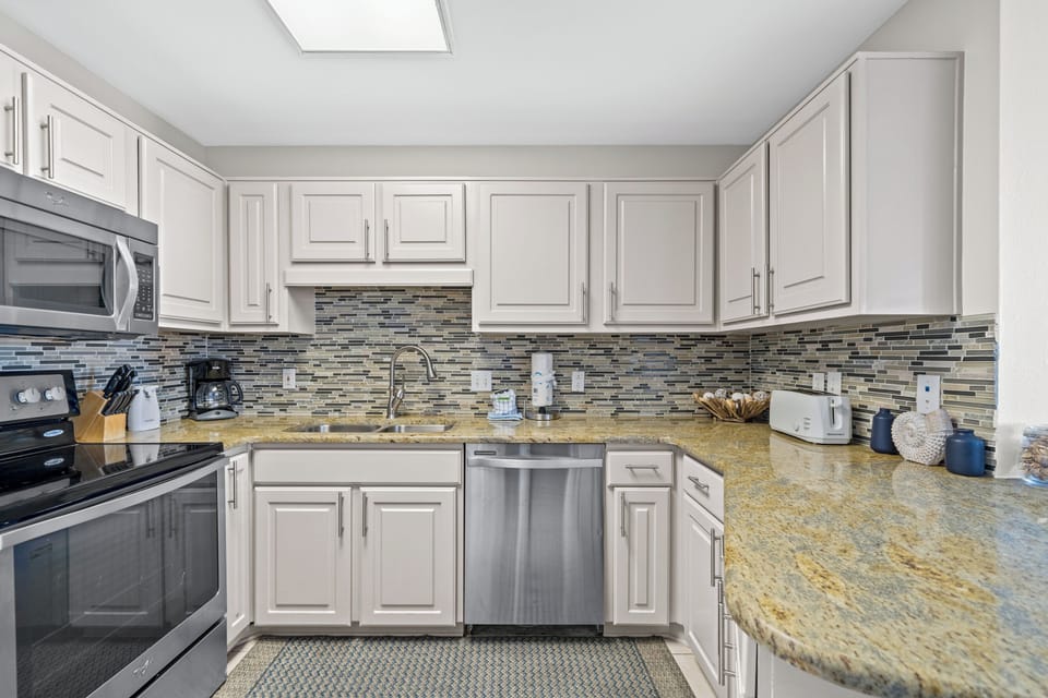Kitchen featuring stainless appliances, granite countertops, and a stylish backsplash, perfect for meal preparation
