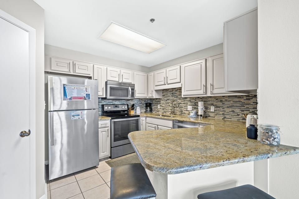 Bright kitchen featuring light cabinetry, stylish countertops, and a breakfast bar with seating for casual dining