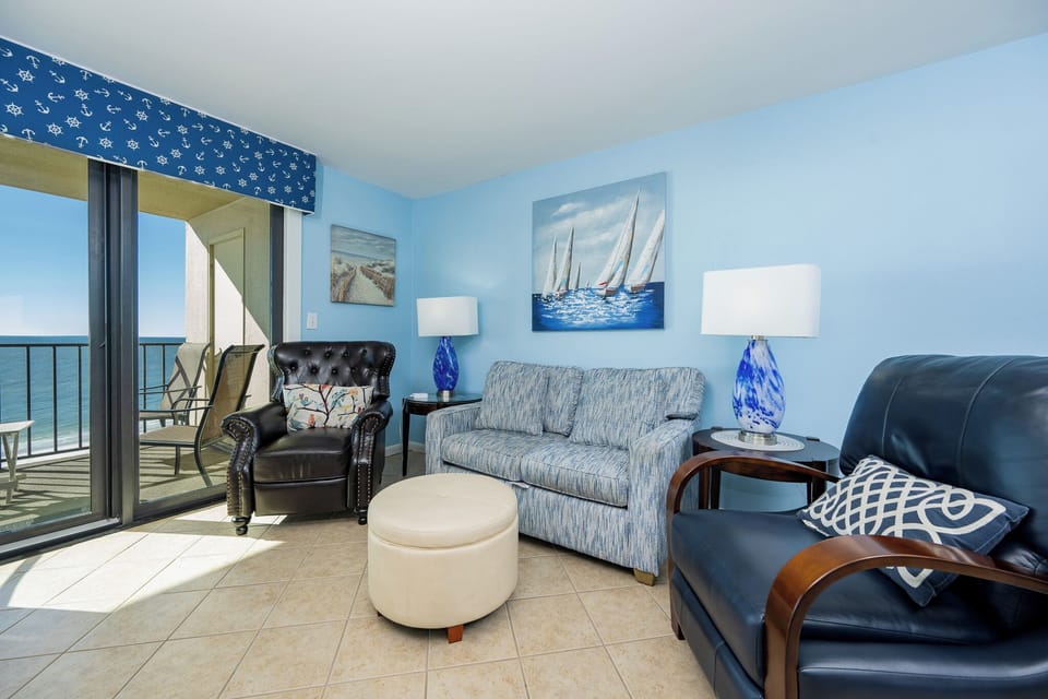 This inviting living area features a cozy blue color palette, comfortable seating, and a breathtaking view from the balcony