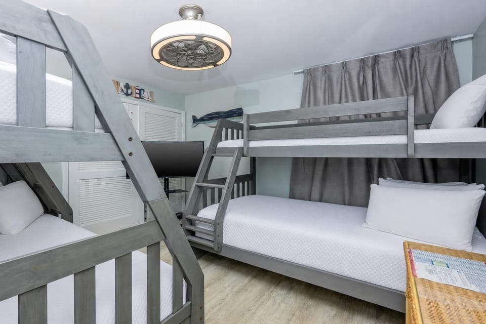 This cozy gust room features two stylish bunk beds, a TV for entertainment, and a nautical decor that enhances the beach vibe