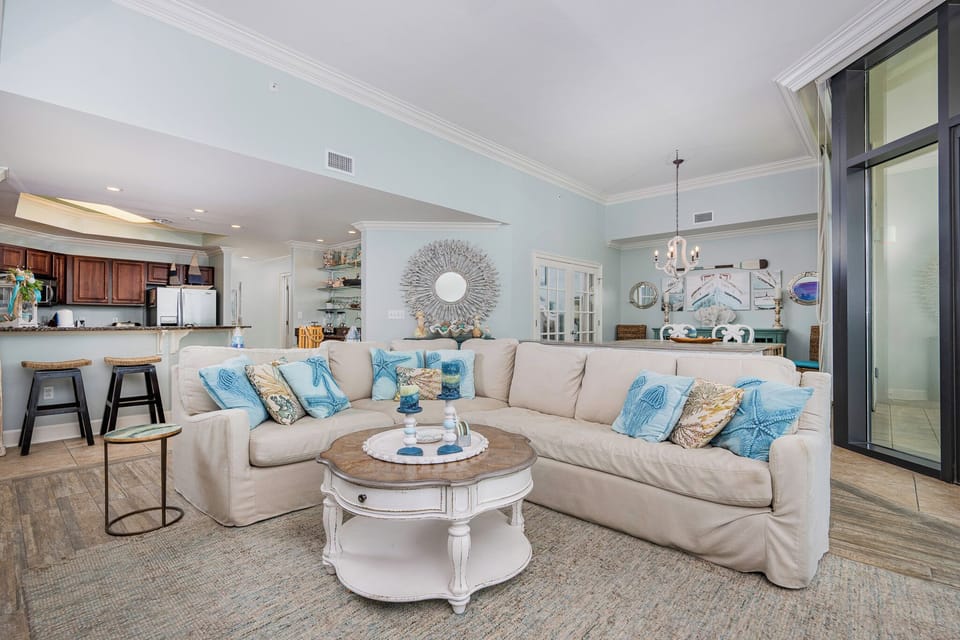 This bright, airy living area features a sectional sofa with ocean-themed accents, perfect for relaxation and entertainment