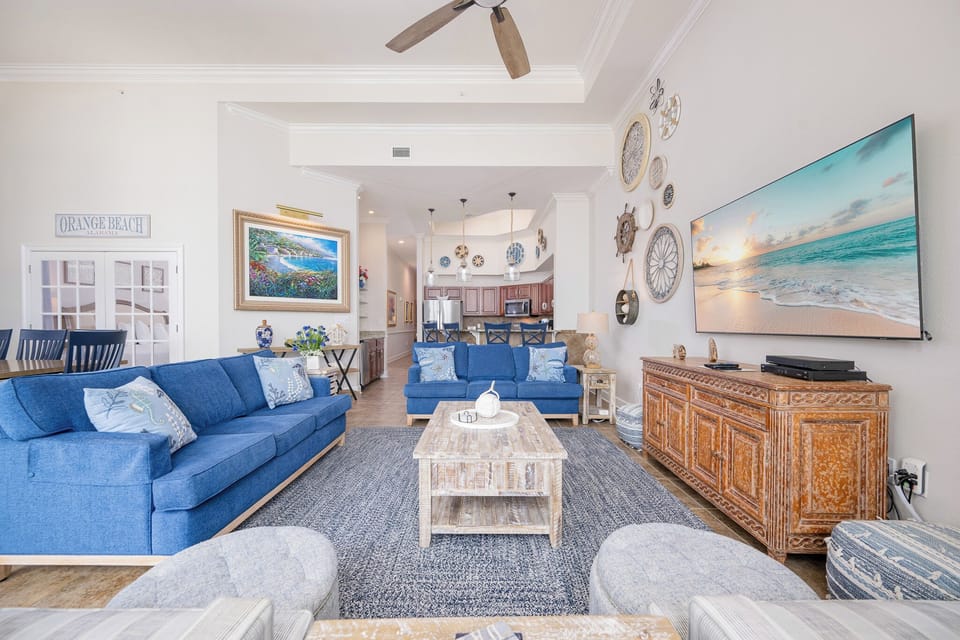Living area featuring blue sofas, coastal decor, and a large TV, perfect for relaxation and entertainment