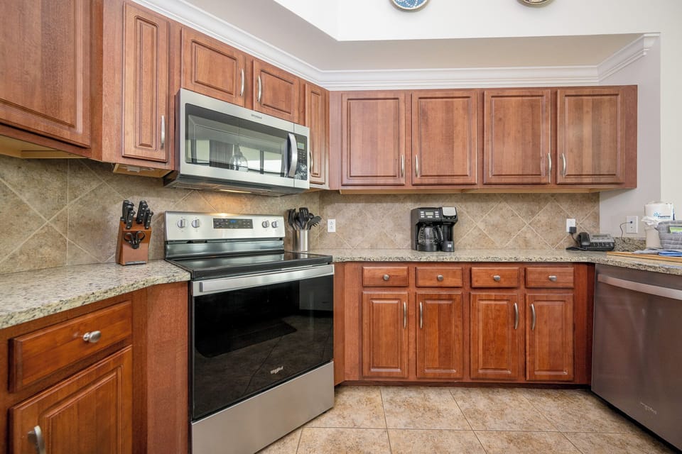 Modern kitchen featuring stainless appliances, granite countertops, and coffee station, perfect for your culinary adventures