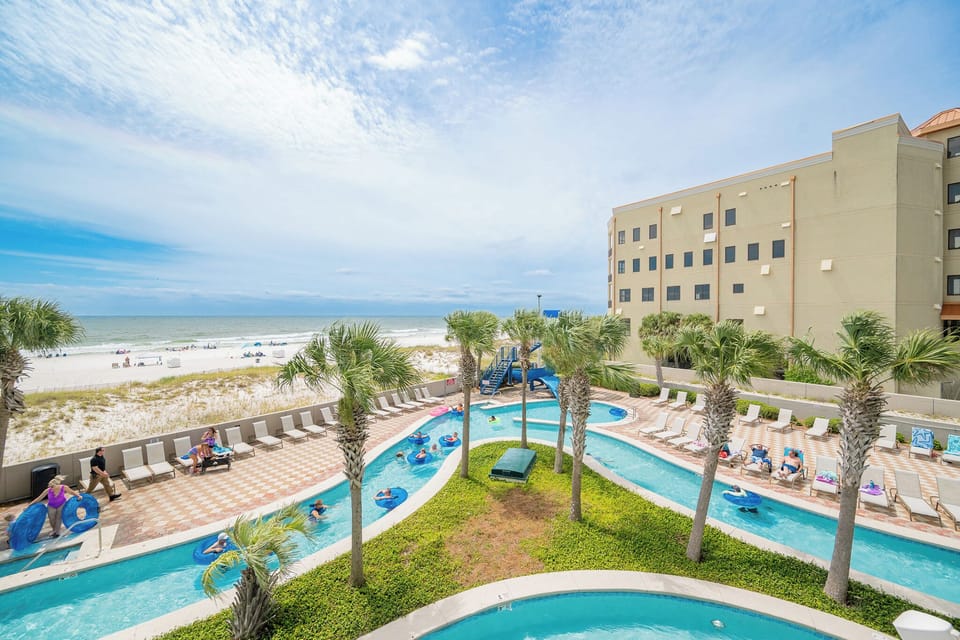 Vibrant pool area of the lazy river from the balcony, surrounded by palm trees creates a perfect tropical escape