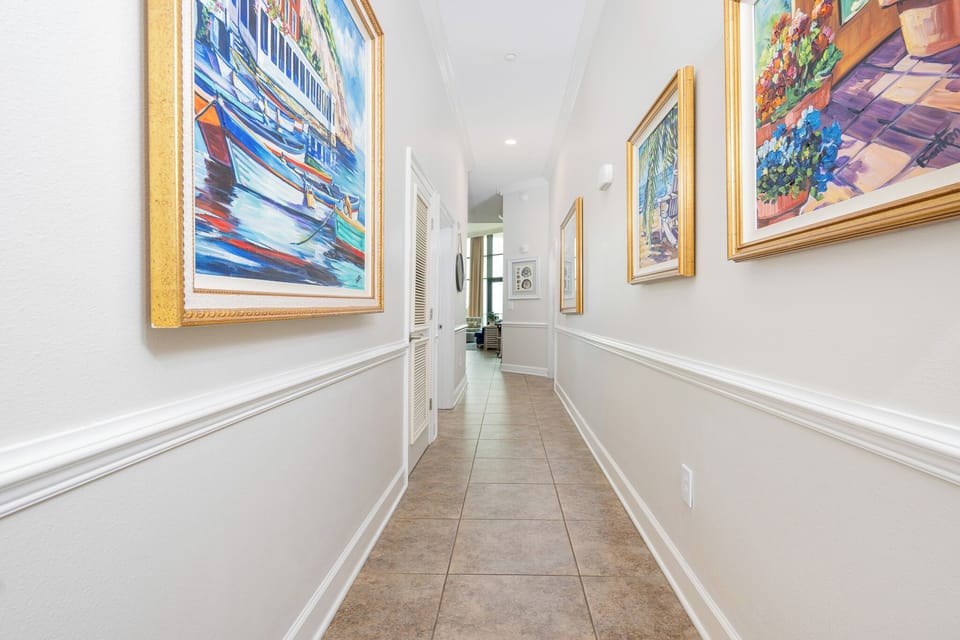 Brightly lit hallway adorned with colorful artwork, leading to a cozy living area with inviting natural light