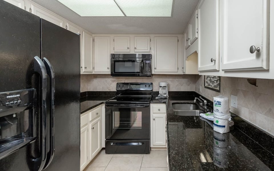 This kitchen features sleek black appliances, granite countertops, and a convenient coffee maker for your morning brew