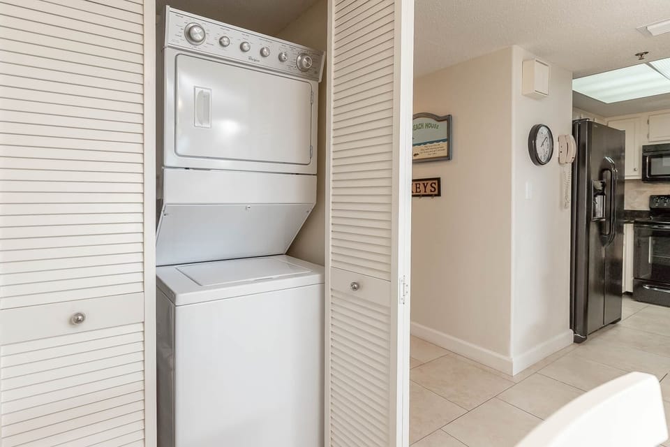 This laundry area features a stacked washer and dryer, seamlessly integrated into the cabinetry for convenience
