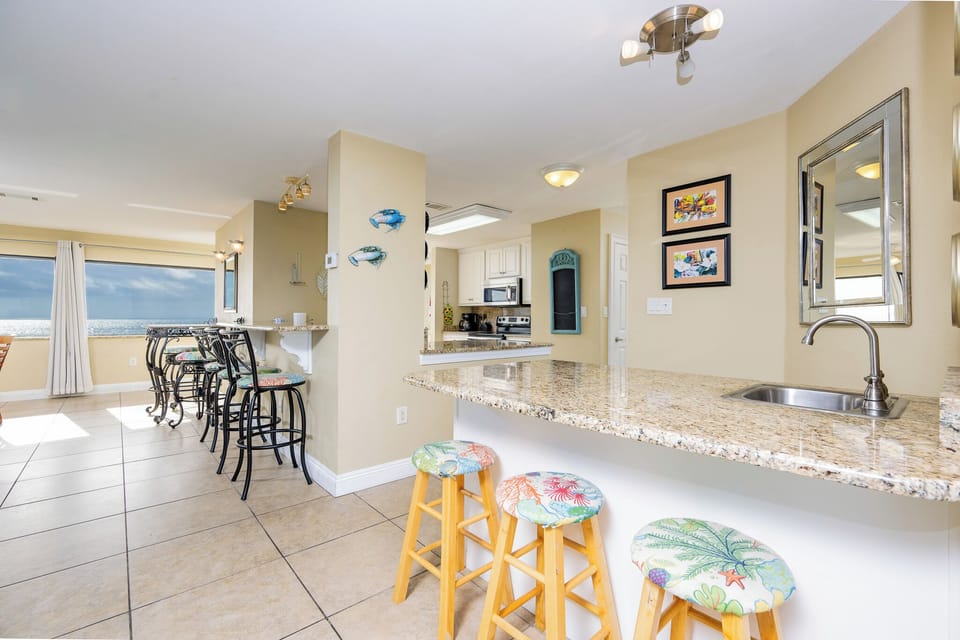 This kitchen features granite countertops, stainless appliances, and a beach view, perfect for cooking and entertaining