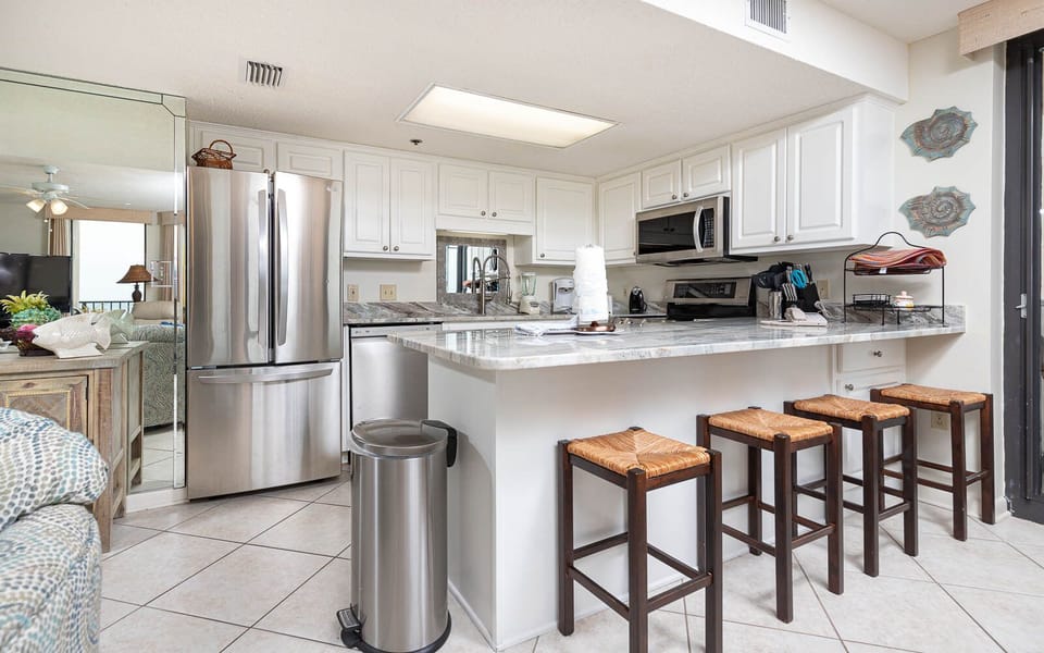 Gather around the spacious kitchen bar, featuring sleek countertops and seating for casual dining or morning coffee