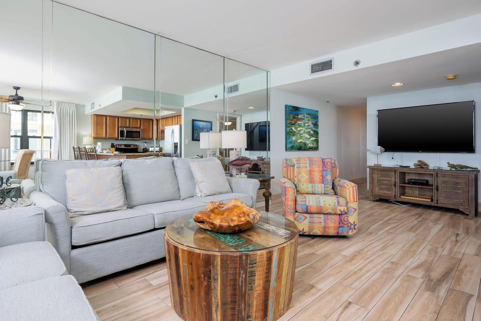 Living room featuring a cozy sofa with queen sleeper, colorful armchair, and a sleek TV for relaxation and entertainment